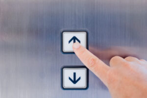 Hand pressing up button illustrating elevator music