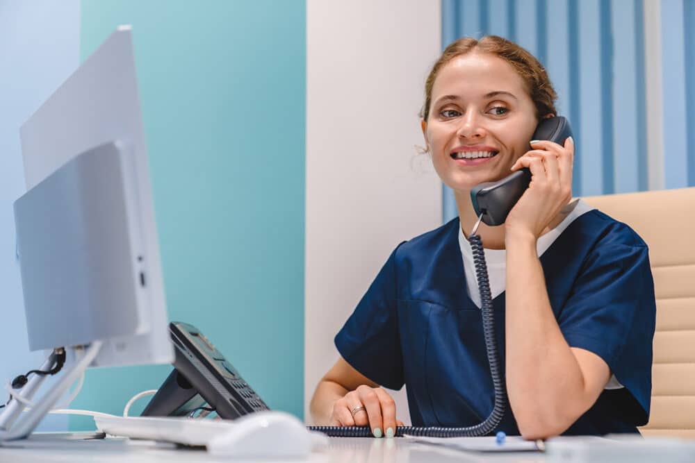 Easy On Hold | Blog - Dental clinic receptionist on phone putting client on hold